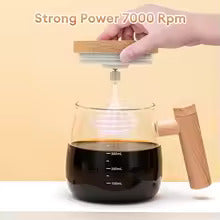 Hand pouring liquid into a glass container with a wooden lid and handle on a beige background.