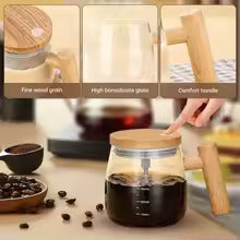 Glass coffee maker with wooden handle and lid on a wooden surface with coffee beans and a cup in the background.