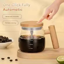 Glass coffee maker with wooden handle on a wooden coaster, surrounded by coffee beans and a lime.